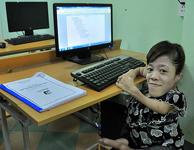 person with small arms and legs, sitting in front of computer